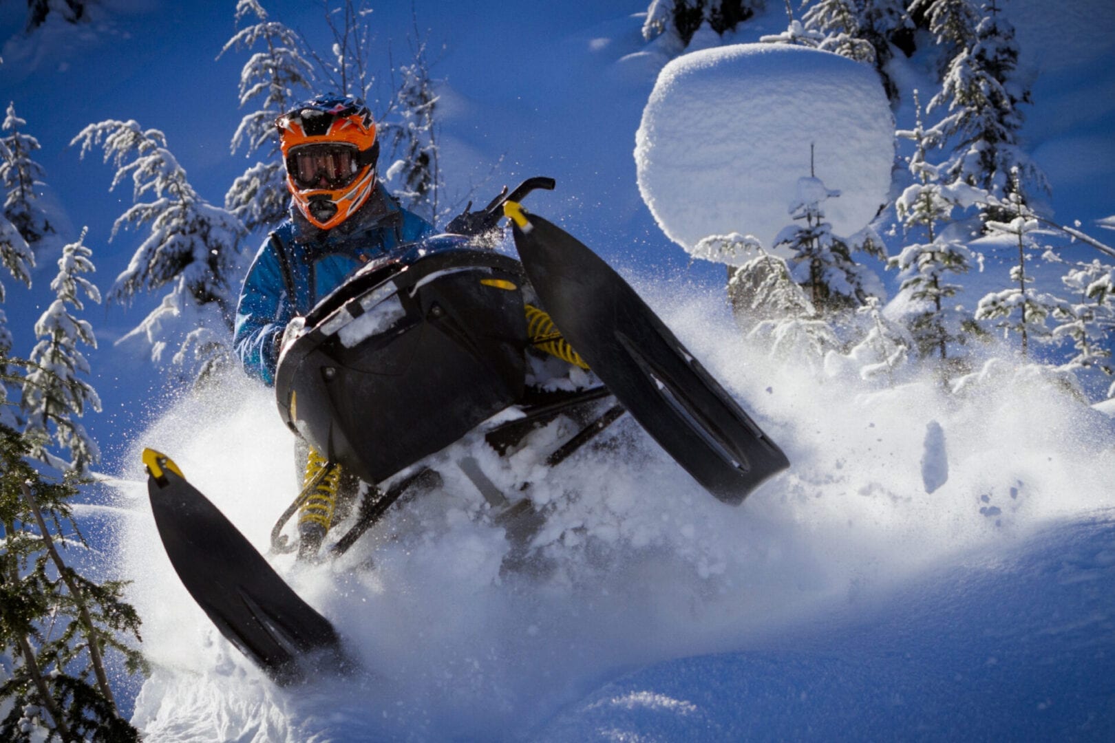 Snowmobiler in deep powder snow in back country using AMSOIL snowmobile oil