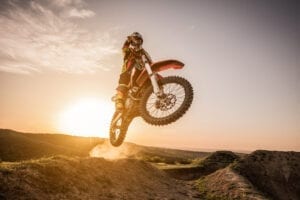 dirt bike jumping at sunset on off-road terrain