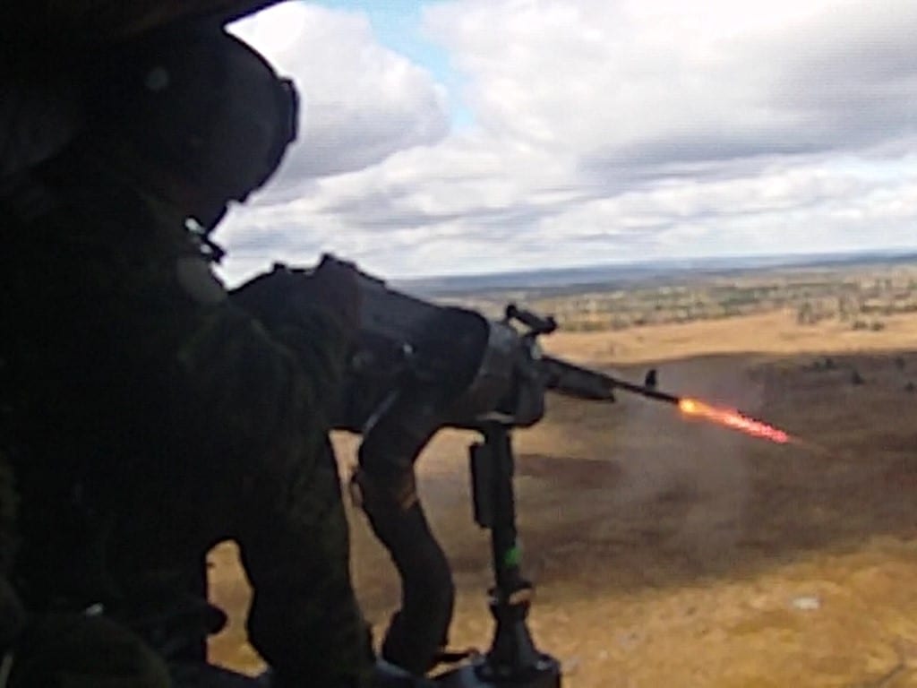 soldier firing a machine gun from a helicopter