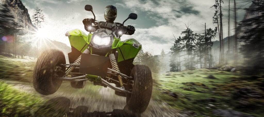 Rider on an ATV tearing through the forest trail, representing off-road enthusiasts who use AMSOIL for extreme performance.