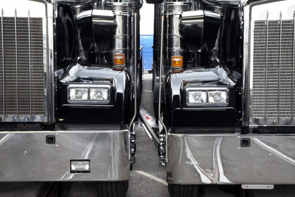 two black transport trucks parked side by side.