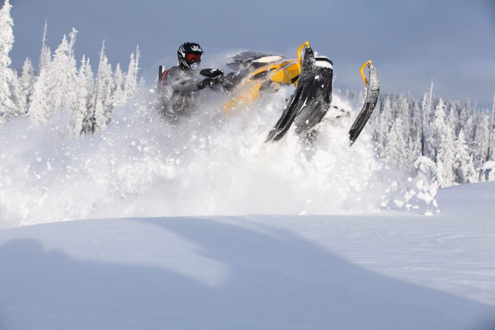 Yellow snowmobile driving in powder snow