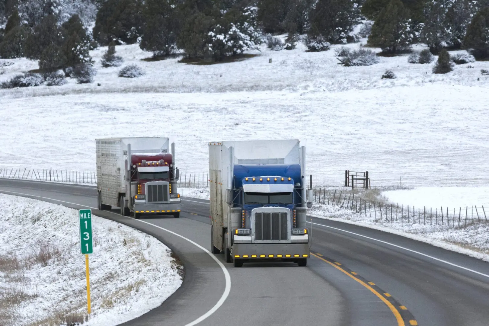 Two transport trucks rounding a bend on a winter road.