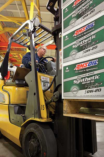 A forklift moving AMSOIL synthetic lubricant products in a warehouse distribution center.