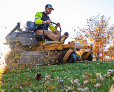 riding lawnmower cutting grass and blowing leaves